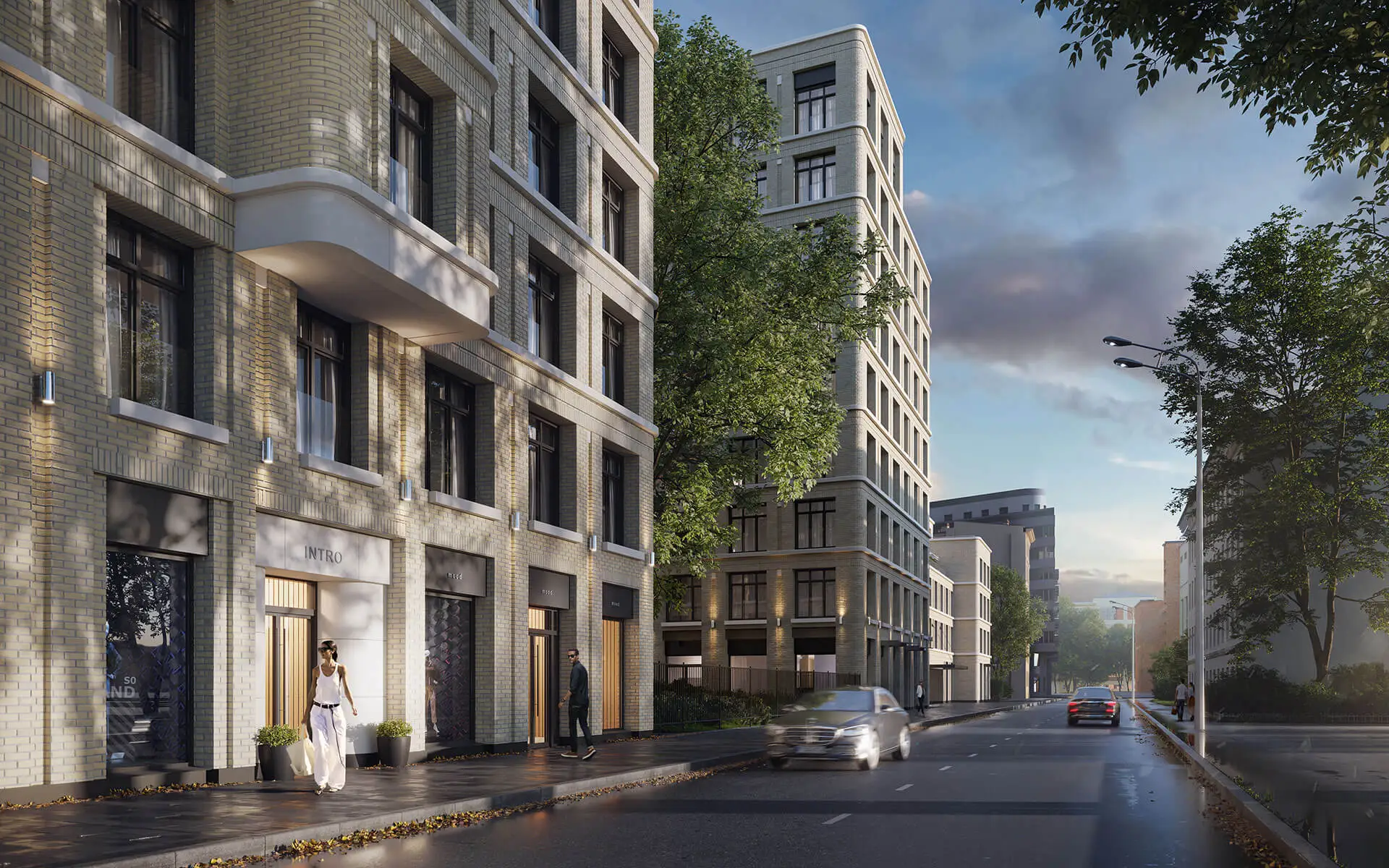 Уличный вид на клубный дом «Визионер» в вечернее время с теплым освещением витрин и современной архитектурой